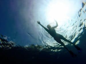 Photo taken from below, looking up at Shev snorkeling on a sunny day in Huatulco