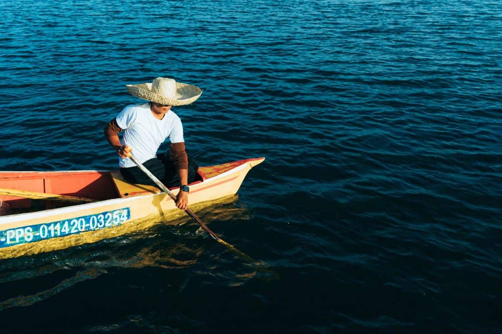 a man fishes from his small boat off the coast of Puerto Angel, Oaxaca