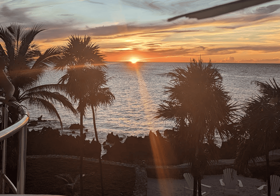 an orange sun sets over the ocean in front of tranquil seas ecolodge and dive resort in Roatan