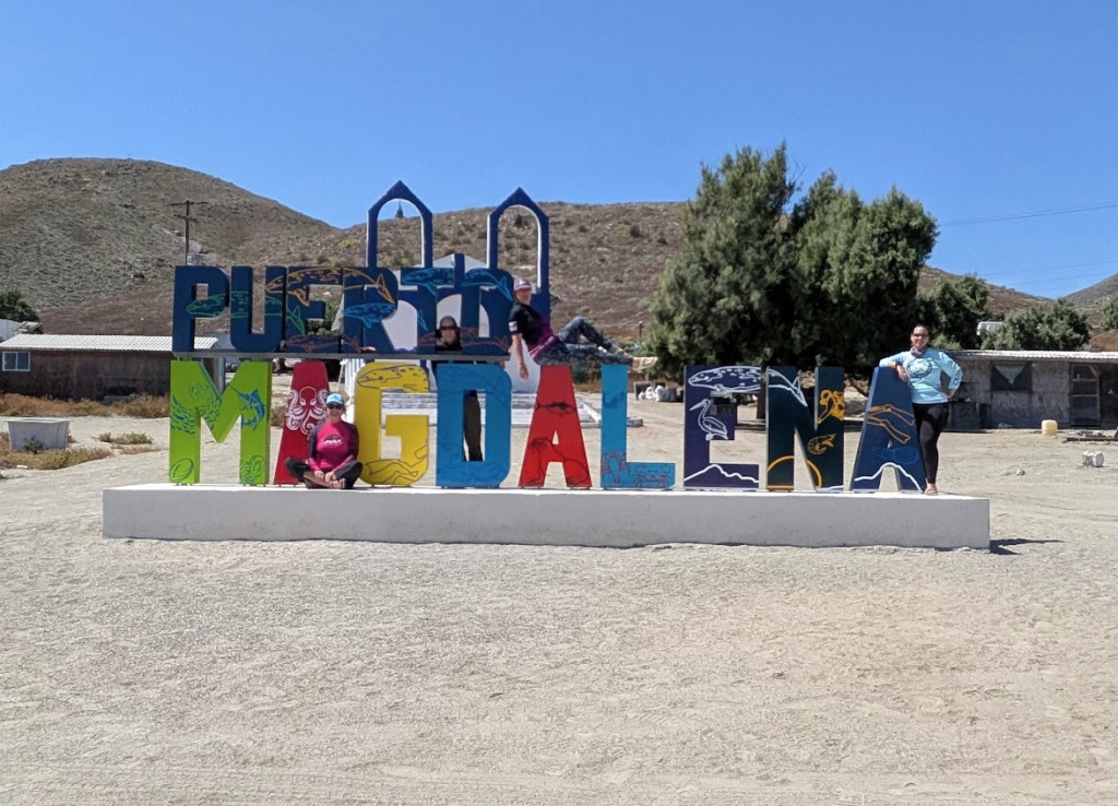 shev and the fam sit around the colourful letters that spell out puerto magdalena in magdalena bay