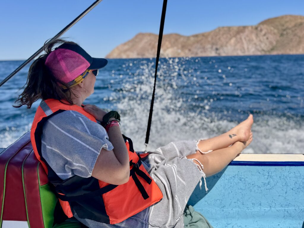 Shev relaxes on the boat in her towel poncho and life vest, after watching the blue whales in loreto